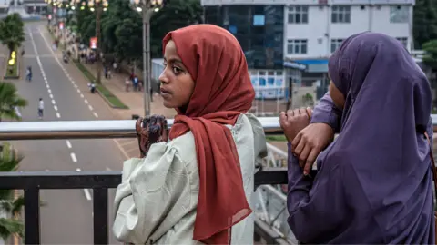 Two young women looking over a bridge on to a newly built roads near a monument in Addis Ababa - May 2026