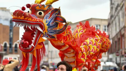 Pacemaker Chinese dragon float, which is mostly red and yellow, being held aloft