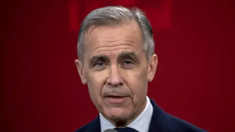 Mark Carney looks into the camera for a portrait in front of red background.