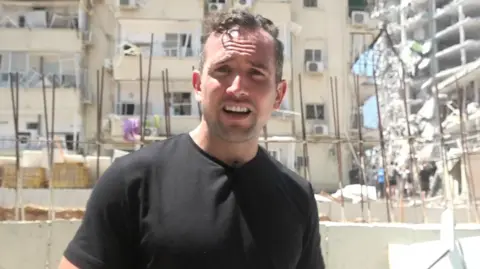 Hugo Bachega in front of a damaged building in Israel's Bat Yam
