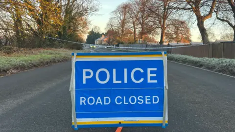 Harriet Heywood/BBC A blue sign in the centre of the road reads 'Police Road Closed. Behind the sign is blue police tape, cordoning off part of Great North Road. 