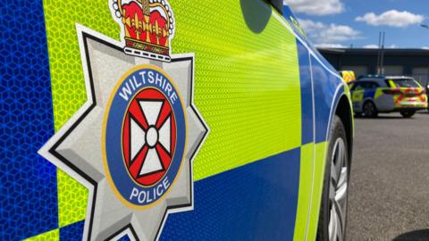 A close-up shot of the badge on the side of a Wiltshire Police car