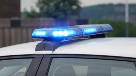 A stock image of blue lights flashing on top of a police car