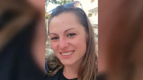 Family Handout Victoria Taylor, a woman in her thirties wearing sunglasses on her head and shoulder-length brown hair, smiles into the camera.