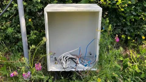 Jack Maclean/BBC Broken white box with cut white and blue wires.
