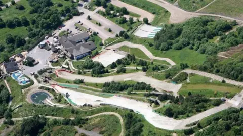  An overhead image of the former ski village in Sheffield showing dry slope runs, grass and trees and buildings.
