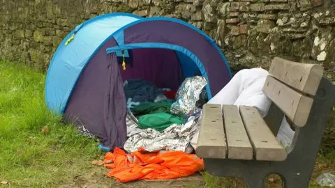 Tent by park bench unzipped showing foil blankets used for warmth