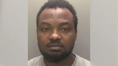 Humberside Police A police custody picture of a man with black hair and a cropped black beard and moustache. He is wearing a light-grey T-shirt and has an emotionless expression.