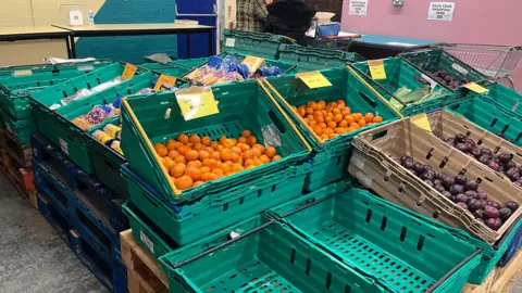 Fruit and bagels in crates. Some crates are empty.