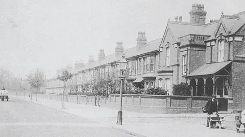 Unknown Old black and white photo of Carholme Road with the house in the corner and a man with a wheelbarrow and another man with a trailer in the distance