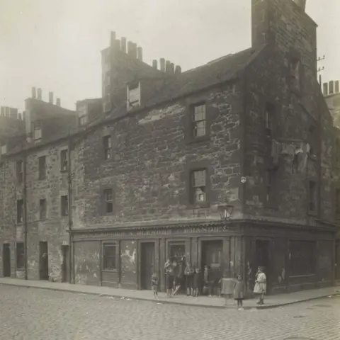 City of Edinburgh Council – Libraries www.capitalcollections.org.uk A black and white photograph of Fox Street in Edinburgh. Children play on the corner but are too small to make out what they are wearing.