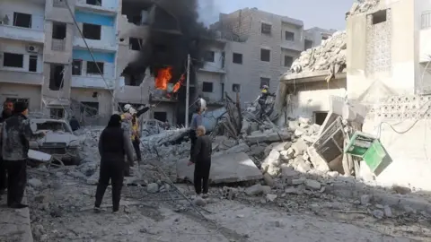 Reuters Screengrab of video supplied by first responders from the Syria Civil Defence, known as the White Helmets, showing the aftermath of an air strike on the rebel-held city of Idlib, Syria (2 December 2024)