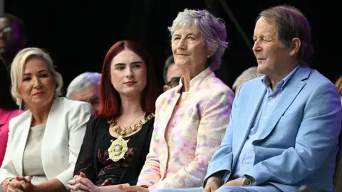Getty Images A woman with blonde hair and a cream suit is seen sitting alongside a woman with red hair and a black top who is wearing a mayoral chain. Beside her is a a woman with short grey hair wearing a light floral jacket and a man beside her with brown hair and wearing a cornflower blue shirt and suit. 