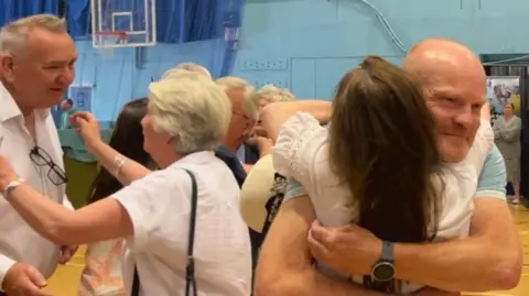Two men hug women in a sports hall
