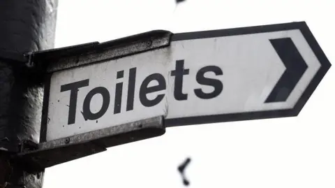 A sign with "Toilets in black writing.