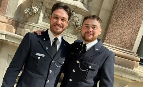 Leicestershire Police Two police officers in ceremonial uniform stand arm in arm