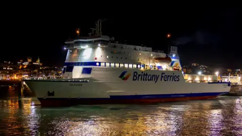 Brittany Ferries A picture of a ferry travelling through the water. It is a large white boat with the word Brittany Ferries on the side of it. It is blue and red in colour.