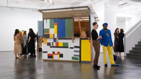 London Gallery Weekend/Linda Nylind A handful of people dispersed around the gallery, around a multicoloured shack.
