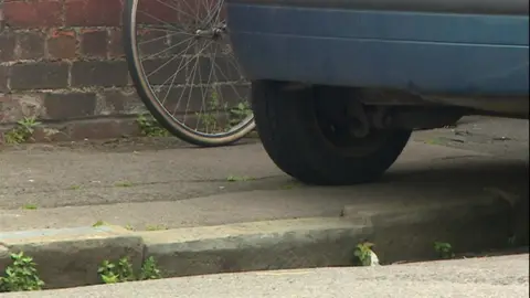 A car with its wheels on the pavement of a road.