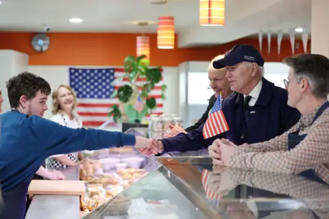 EPA Joe Biden shakes the hand of a young man at a food shop in Dundalk