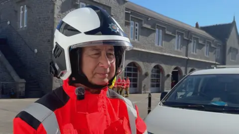 A man with grey hair in fire services uniform in a fire station