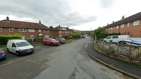 A street view image of a road in the middle of a residential estate. 