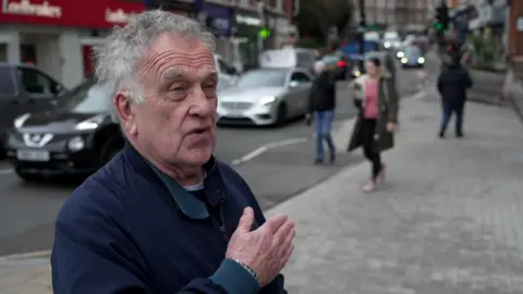 A man looks cross and gesticulates at a pavement