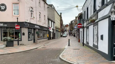 BBC A picture of Friars Vennel a narrow road wending its way through Dumfries with a paved roadway