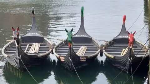 VIKING LONGBOAT RACES The three replica boats tied up in Peel Harbour, they have Viking style dragon heads on the front.