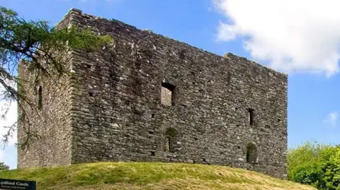 A stonebuilt castle on a grassy mound
