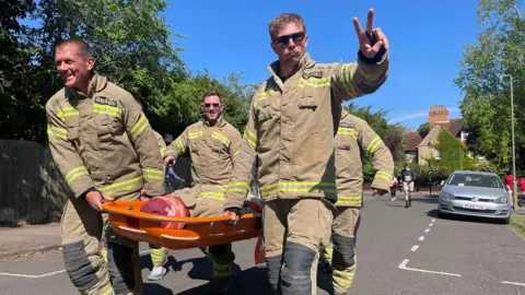 Oxfordshire Fire and Rescue Service Firefighters carrying the mannequin on a stretcher through a North Oxford street.