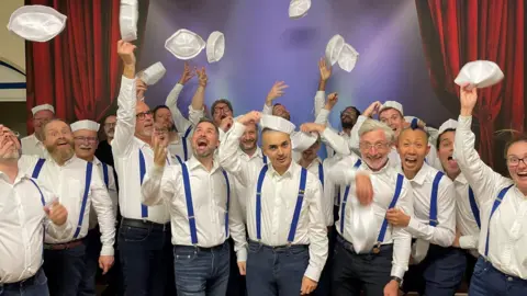 BRISTOL GAY MEN'S CHORUS LGBTQ+ choir throw their hats in the air whilst dressed as sailors
