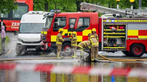 Aodhán Roberts A fire engine with four fire fighters standing in front of it 