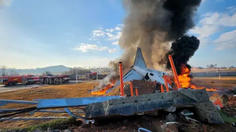 Reuters/Yonhap Part of a plane burns next to the runway 