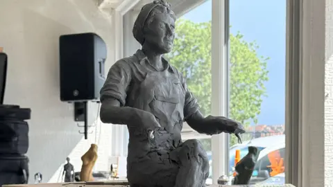 Supplied A maquette of the statue. It shows the artwork in progress. The model is of a female steelworker who is seated with her legs crossed.