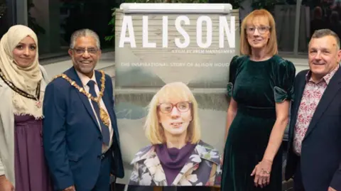 UHNM Charity Alison Hough and others stood by an image of her 