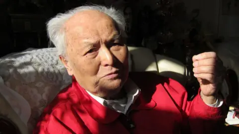 Li Rui, seen before his death, wears a red jacket and a white collared shirt