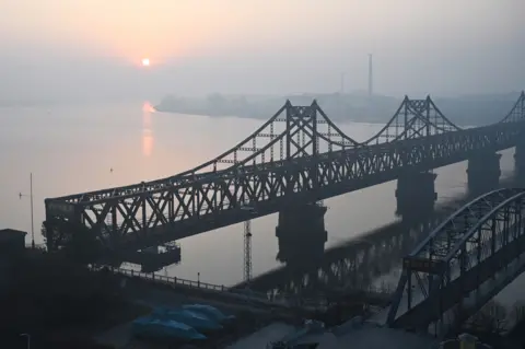AFP via Getty Images A recent picture of the sun rising over the North Korean town of Sinuiju, behind the Sino-Korean Friendship Bridge (left) and the Yalu River Broken Bridge (right), as seen from the border city of Dandong