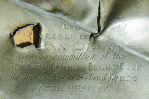 Filip Krapels In the top left, jagged edges indicate that a high-velocity round has passed through the silver, rendering some of the writing indistinguishable
