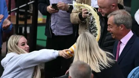 Getty Images A woman throwing a milkshake at Nigel Farage while he is campaigning in Clacton-on-Sea