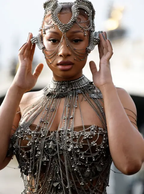 Getty Images Megan Thee Stallion wearing an elaborate outfit with lots of metallic wires coming out of a metal neckpiece, and a headpiece made from shaped wires 