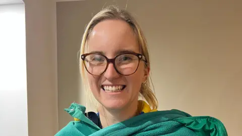 Handout Lily Young, a blonde woman wearing glasses, is pictured smiling at the camera. 