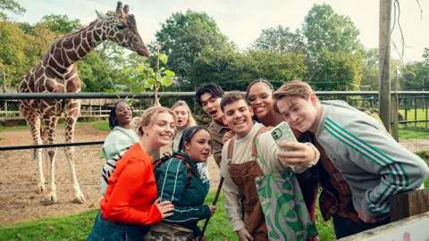 Netflix/See-Saw Films The cast of Heartstopper gather together for a selfie with Bashu the giraffe who is in his enclosure