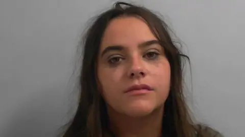 North Yorkshire Police A mugshot of a young woman with long dark hair and running eye makeup. 