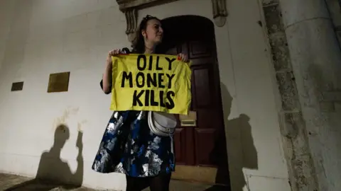 Getty Images A campaigner from climate justice organisation Fossil Free London is ejected from the Guildhall after interrupting a formal gala dinner organised by Republicans Overseas UK to celebrate US President Donald Trump's second state visit to the UK on 16th September 2025 in Windsor, United Kingdom.