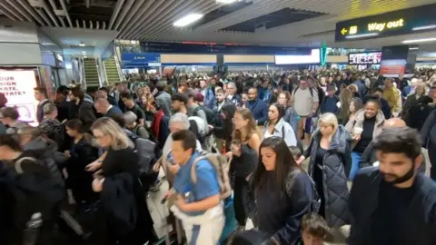 Large crowds of passengers are seen making their way through Euston station as part.