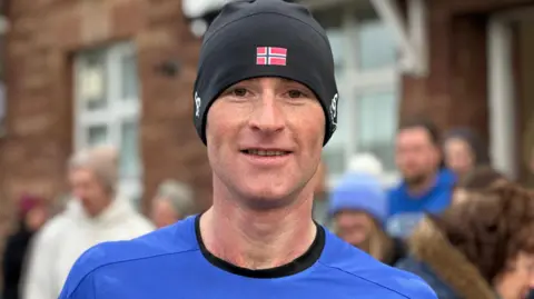 BBC Albert Johnson wearing a blue T-shirt and a black hat.