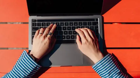 A woman typing on a laptop keyboard