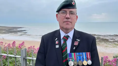 Phil Harrison/BBC Veteran Darren Riley stood above the beach 
