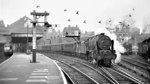 Tom Boustead A steam train moving alongside a platform
